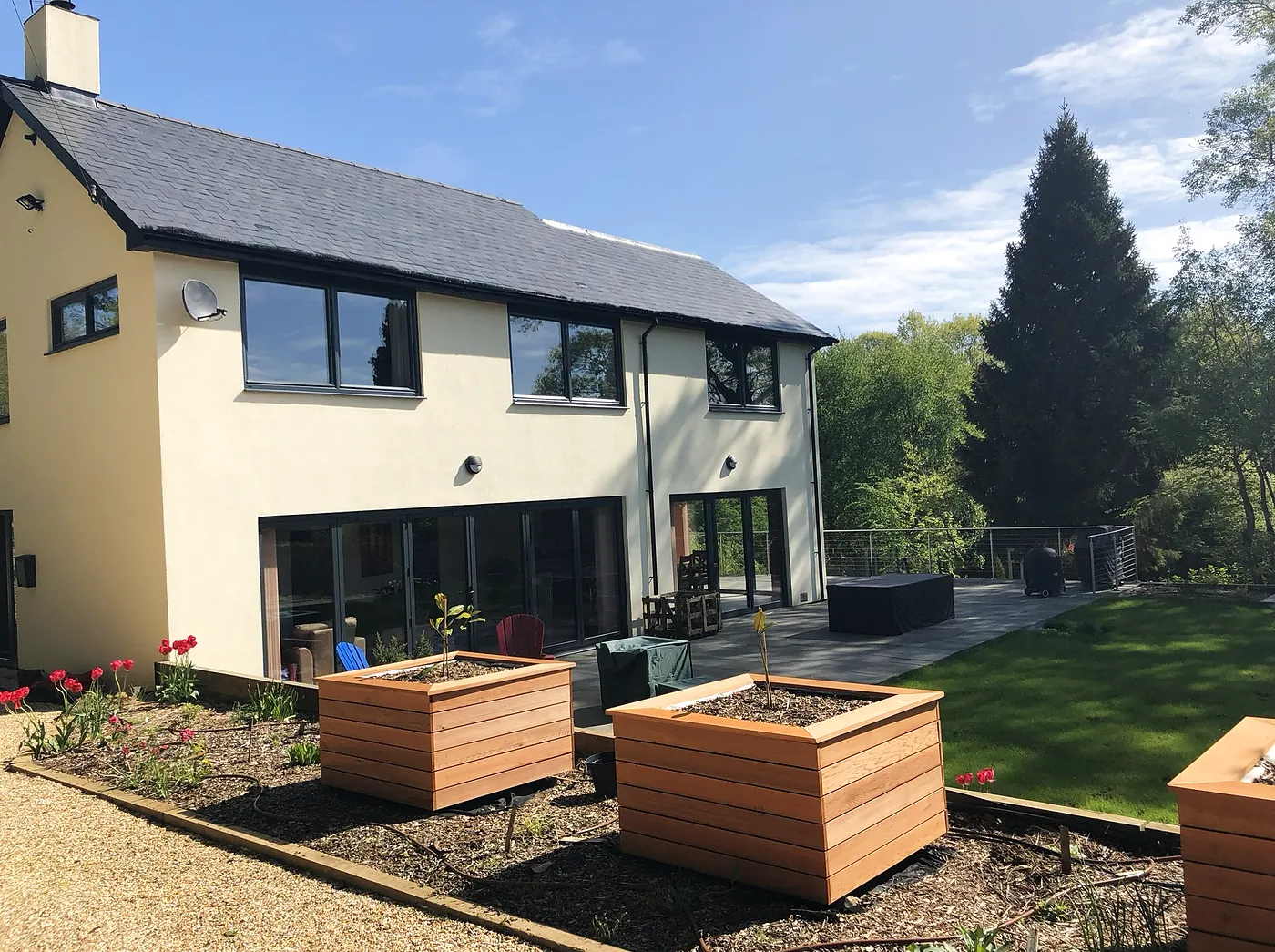 The finished house, rendered and extended, with bifold doors onto the patio and garden