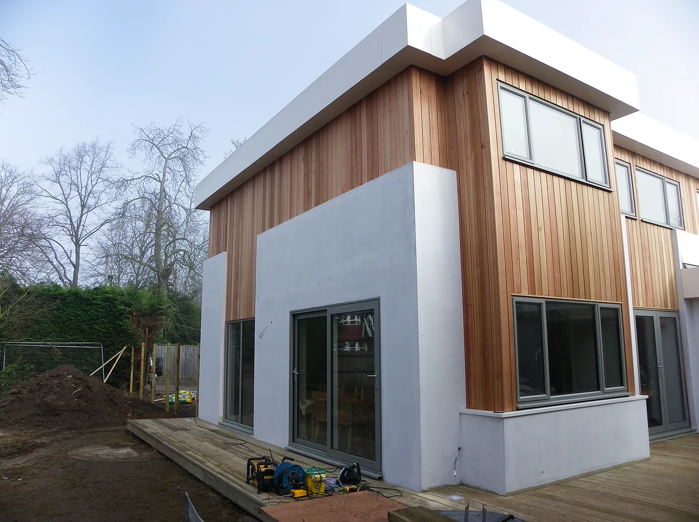 The finished two-storey extension in white render and cedar cladding